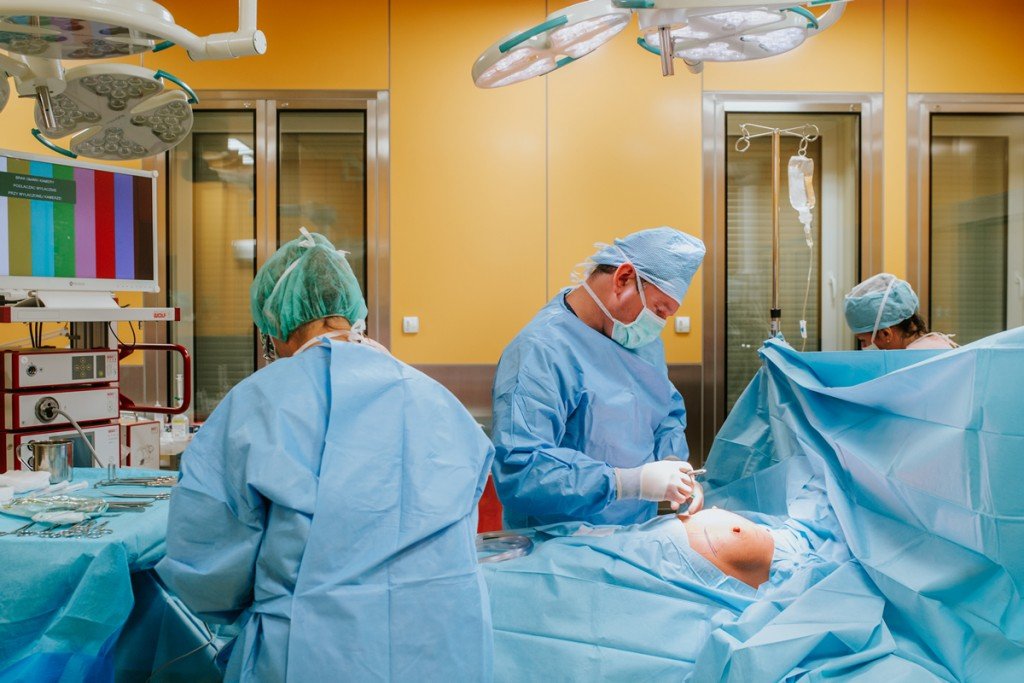 Zespół chirurgiczny w fartuchach i maskach podczas operacji na sali operacyjnej
